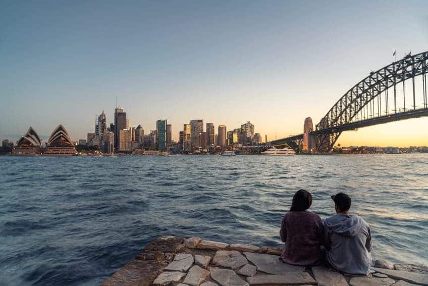 Romantic couple looks at Sydney skyline at dusk.