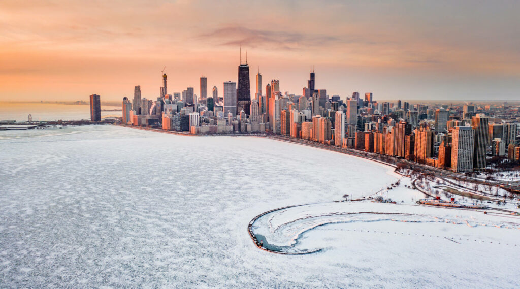 Aerial view of Chicago’s skyline during winter with a frozen Lake Michigan, illustrating the city’s harsh cold weather as a potential drawback.