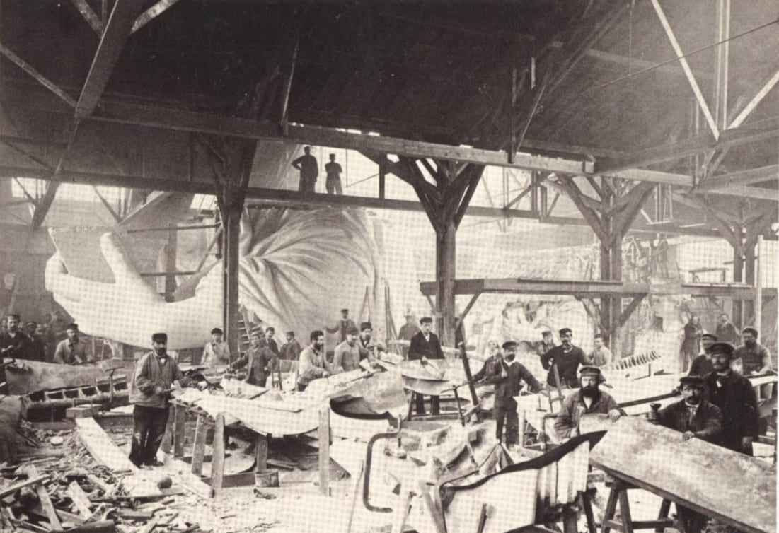 A team of workers hammering sheets of copper during construction