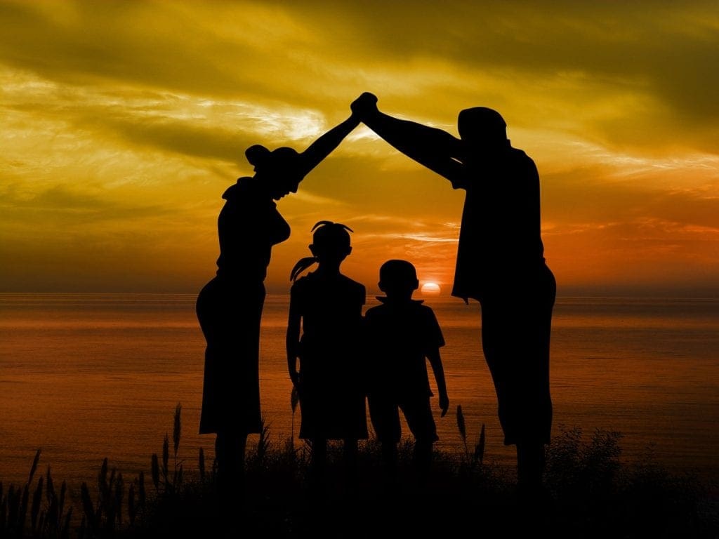 silhouette of a family with a beach and sunset backdrop - pros and cons of living abroad