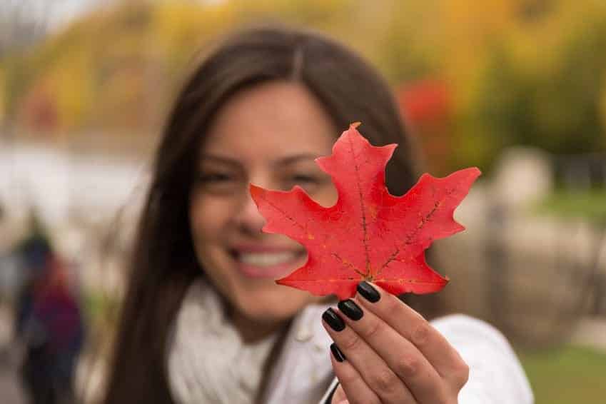 Smiling girl holding red maple leaf (Canada´s symbol)