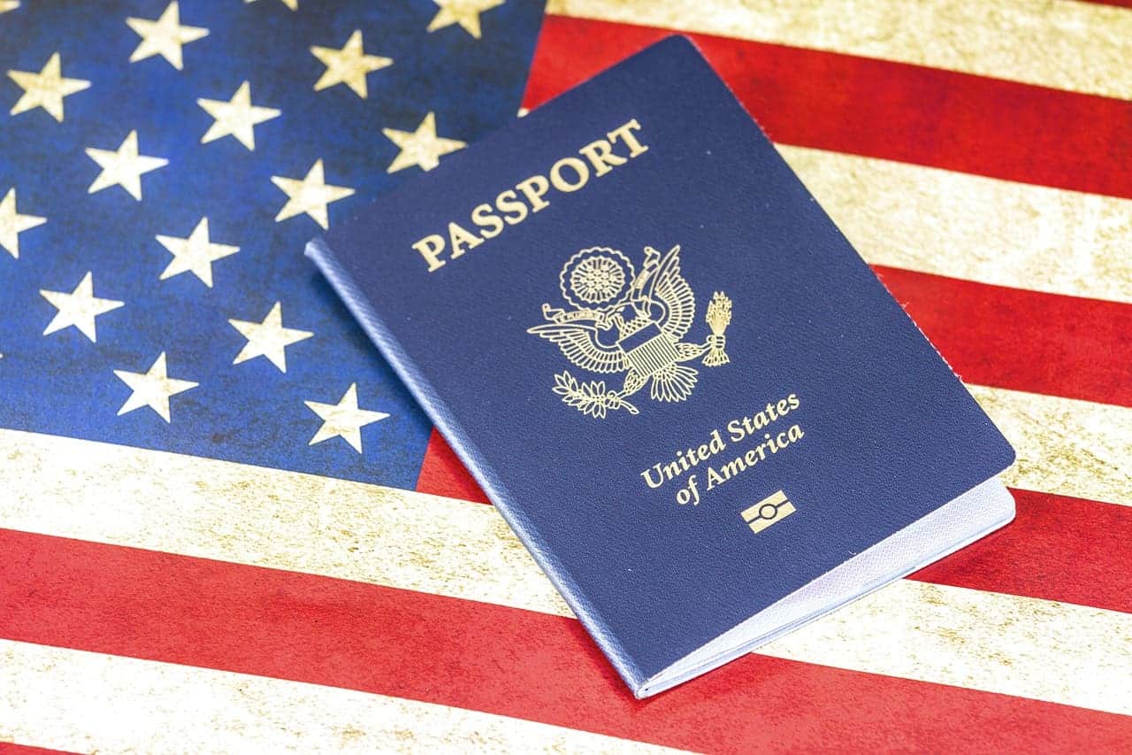 An image of a US Passport with the American Flag in the Background - Immigrating to the USA - How to Immigrate to the USA