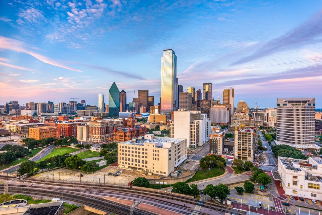 Aerial view of downtown Dallas, Texas, at sunrise with modern skyscrapers and a vibrant cityscape, highlighting the city’s appeal for newcomers.