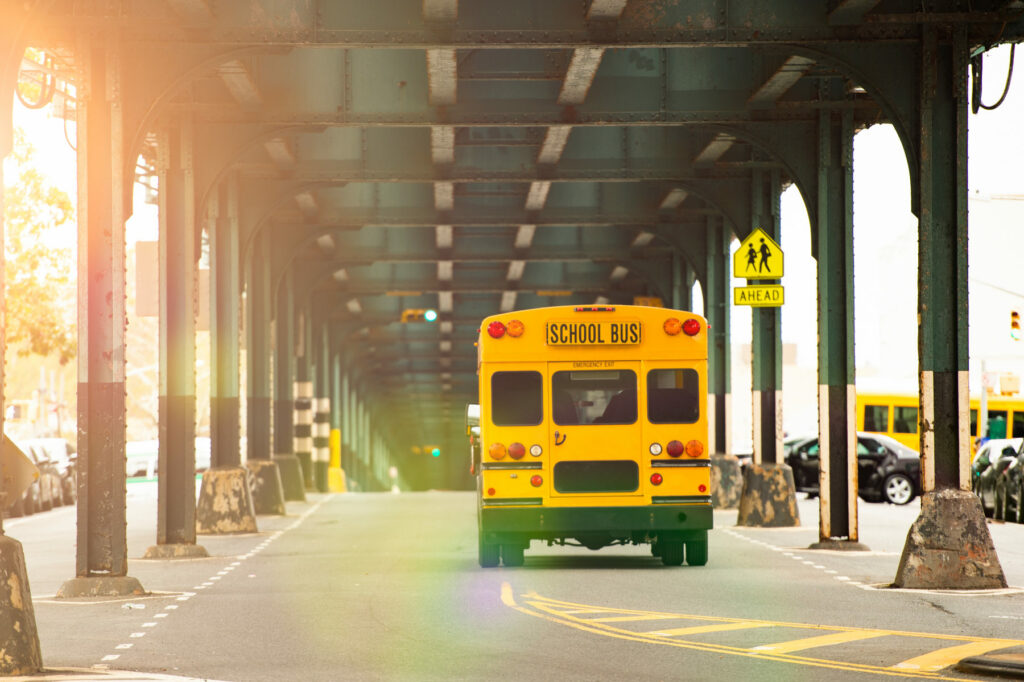 A school bus passing under the railway bridge in the Bronx, New York City, USA.