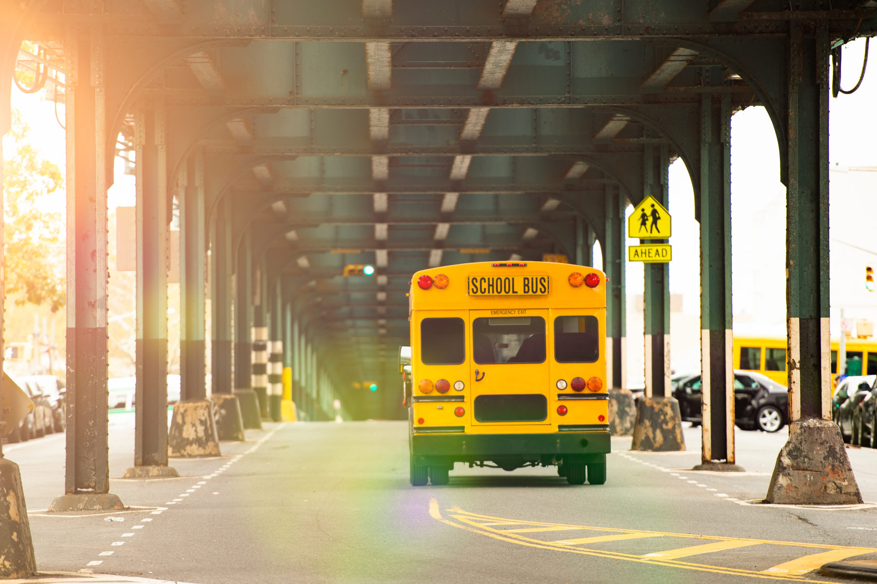 Yellow school bus driving under a bridge in Austin, representing the city's excellent educational facilities.