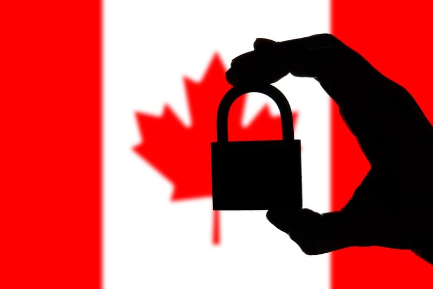 Canada security. Silhouette of hand holding a padlock over national flag