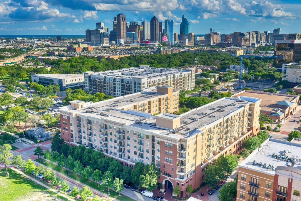 Aerial view of Uptown Dallas with modern apartment complexes and tree-lined streets, showcasing the vibrant, urban neighbourhood and proximity to the downtown skyline.