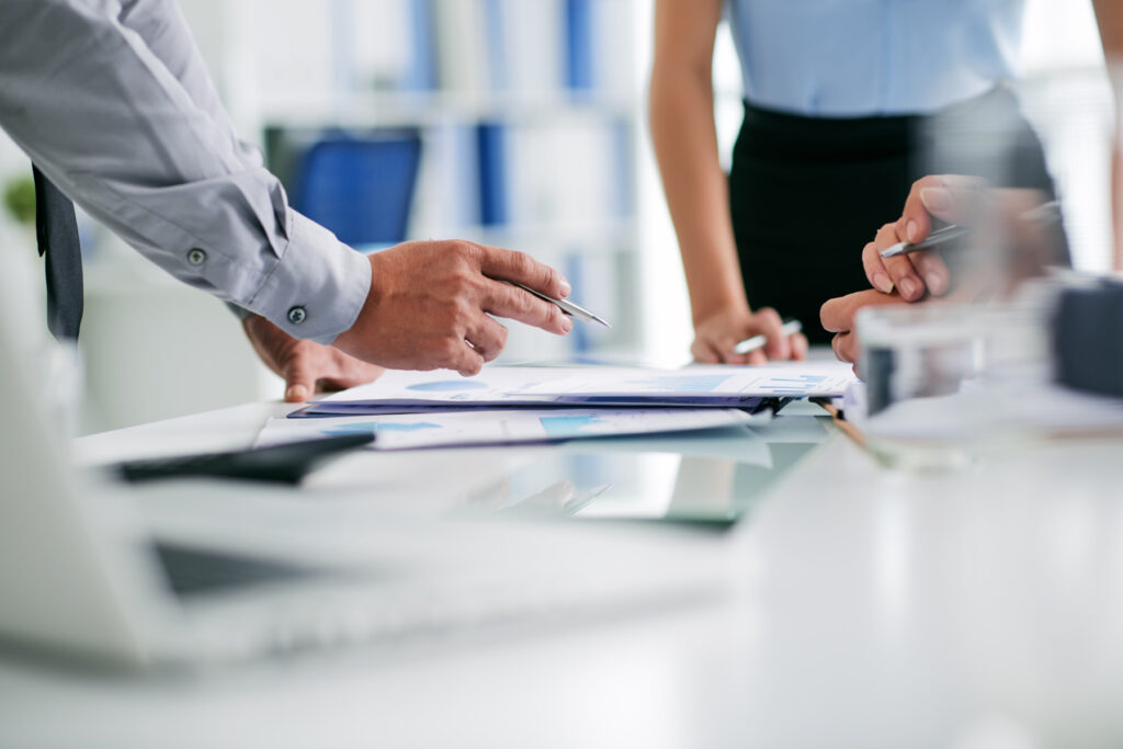 Close-up of business professionals discussing documents at a desk, representing work visas, job opportunities, or relocation planning in Singapore.